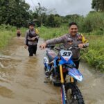 Pantang Menyerah untuk Datangi TPS, Personel Pam Polres Melawi Dorong Sepeda Motor Saat Banjir
