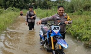 Pantang Menyerah untuk Datangi TPS, Personel Pam Polres Melawi Dorong Sepeda Motor Saat Banjir